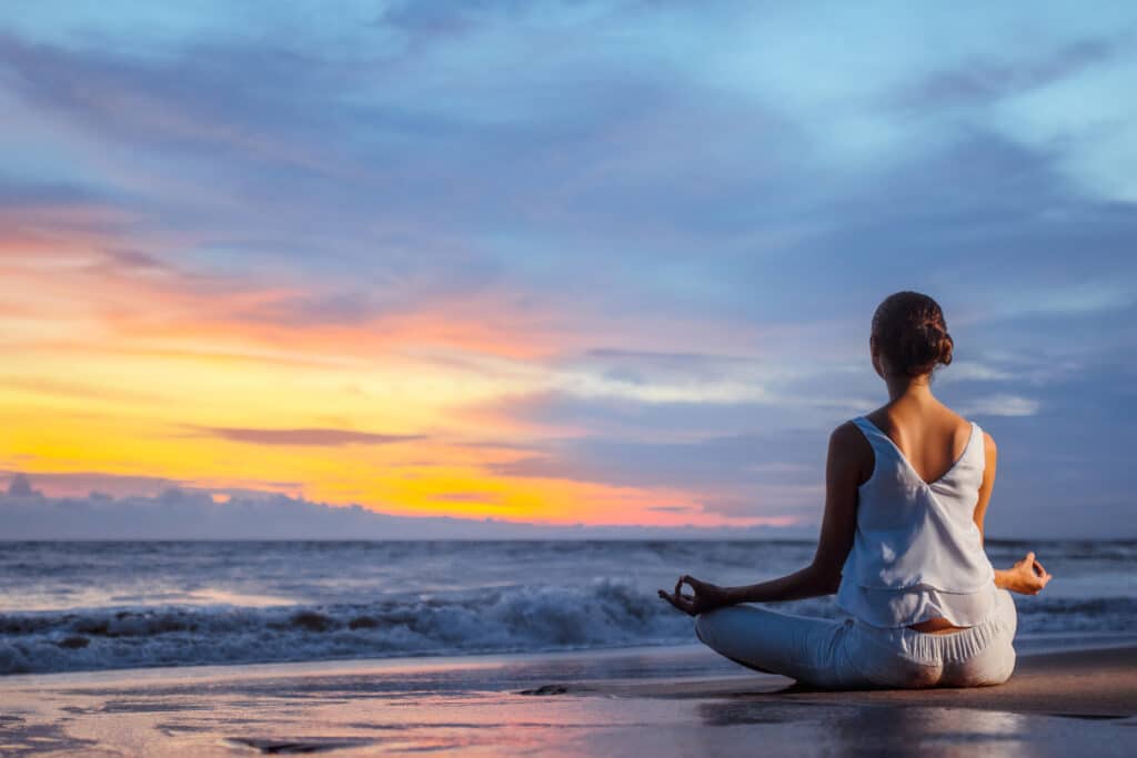 woman meditating on beach - anxiety therapy