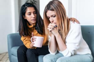 woman holding mug comforting friend with sexual betrayal trauma